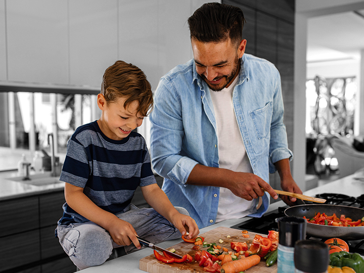 Father and son cutting bellpeppers on cutting board