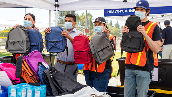 four volunteers holding backpacks